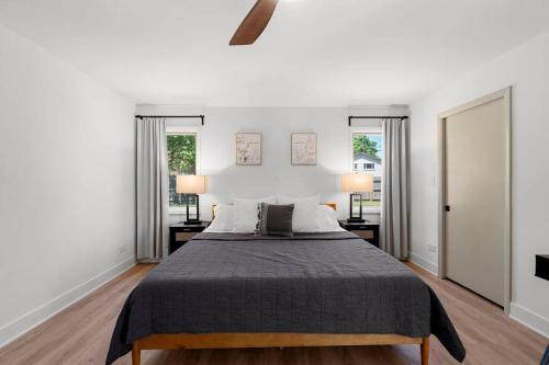a bedroom with a large bed with two windows at New Bensenville Home by O'Hare Airport with Indoor Pool, Sauna, and Arcade in Bensenville