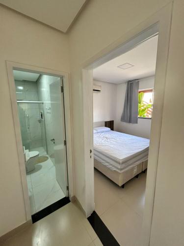a bedroom with a bed and a bathroom with a shower at Pousada Vila das Grutas in João Pessoa