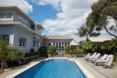 a swimming pool in front of a house at Pohutukawa Point Estate Homestead in Karaka