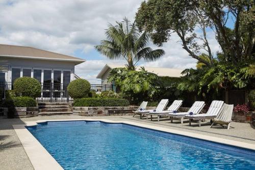 a pool with lounge chairs next to a house at Pohutukawa Point Estate Homestead in Karaka