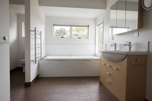 a white bathroom with a tub and a sink at Pohutukawa Point Estate Homestead in Karaka