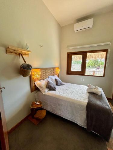 a bedroom with a bed and a window at Cel de Atins Chalé - Lençóis in Atins
