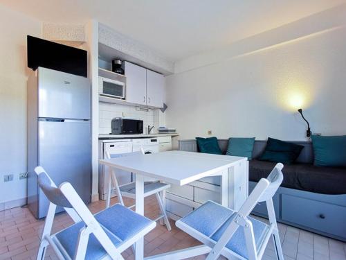 une cuisine avec une table blanche, des chaises et un canapé dans l'établissement Studio en Rez-de-Jardin, 2 Couchages, à 10m de la Plage du Lavandou, Parking, Clim, Tennis. - FR-1-803-10, au Lavandou