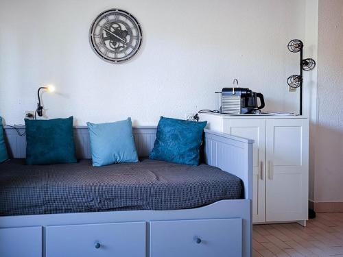 - un lit avec des oreillers bleus et une horloge murale dans l'établissement Studio en Rez-de-Jardin, 2 Couchages, à 10m de la Plage du Lavandou, Parking, Clim, Tennis. - FR-1-803-10, au Lavandou