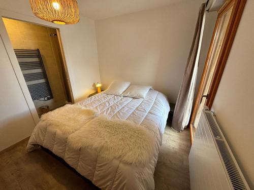 une chambre avec un lit avec des draps blancs et des oreillers dans l'établissement Châtel : Bel appart. 3 pièces avec garage et balcon, 5 pers - FR-1-198-264, à Châtel