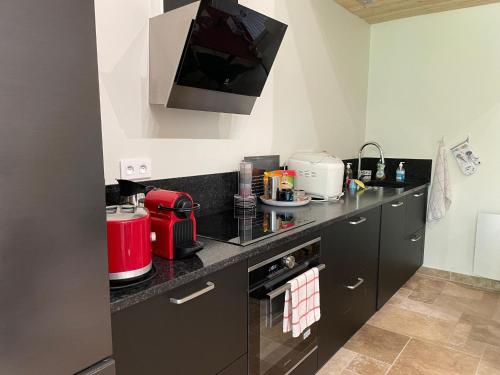 une cuisine avec des comptoirs noirs et un appareil rouge dans l'établissement Échappez-vous à la campagne sarthoise: charme, nature, proximité 24H du Mans & zoo! - FR-1-410-448, à Mayet