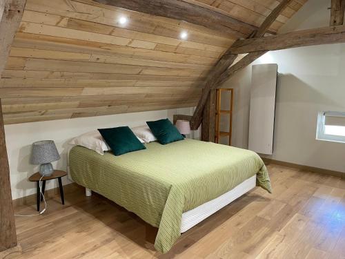una camera con letto verde e soffitto in legno di Échappez-vous à la campagne sarthoise: charme, nature, proximité 24H du Mans & zoo! - FR-1-410-448 a Mayet