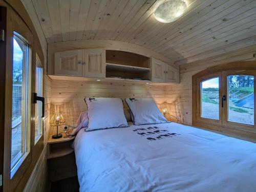 a bedroom with a large bed in a tiny house at Roulotte cosy avec jacuzzi et spa, massages bien-être, nature et calme, près de Lyon - FR-1-582-477 in Monistrol-sur-Loire