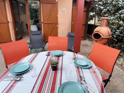 - une table avec des assiettes et des ustensiles en haut dans l'établissement Villa Patio 4 Couchages, Plage à Pied, Surf Spot, Wifi, Parking, Capbreton - FR-1-239-1078, à Capbreton