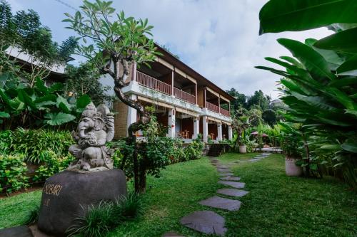 a garden with a statue in front of a building at Sanubari Ubud in Ubud