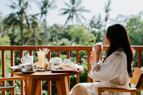 a woman sitting at a table with a cup of coffee at Sanubari Ubud in Ubud