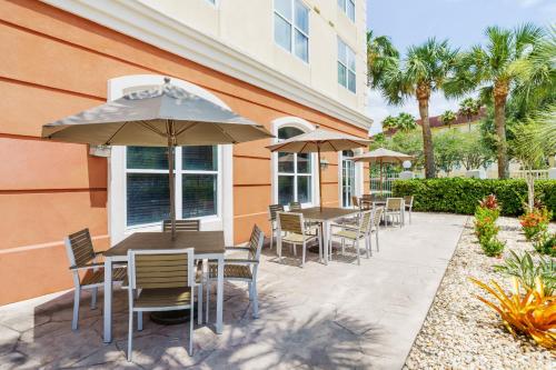 a patio with tables and chairs and an umbrella at Country Inn & Suites by Radisson, Orlando Airport, FL in Orlando