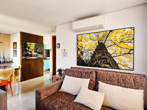 a living room with a couch and a painting on the wall at Solar da Encosta 305 - Espaço e conforto no Centro in Gramado