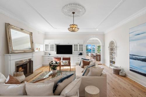 a living room with white furniture and a fireplace at Kaya in Collaroy