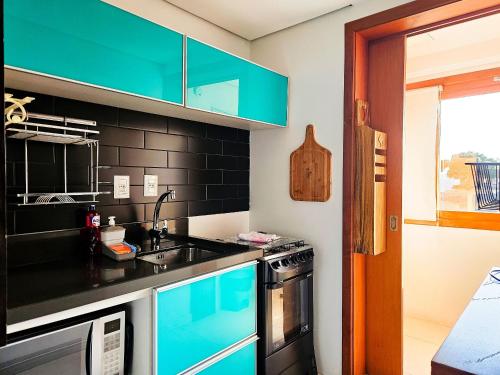 a kitchen with blue cabinets and a sink at Solar da Encosta 305 - Espaço e conforto no Centro in Gramado