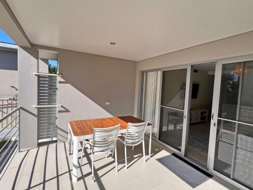 a balcony with a wooden table and chairs at Cool and Calm - Bring your own linen in South West Rocks