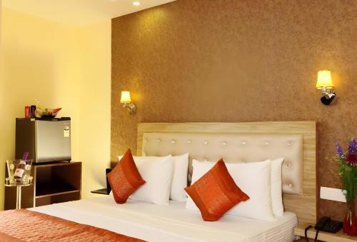 a bedroom with a bed with orange and white pillows at Hotel Aeroporto in New Delhi