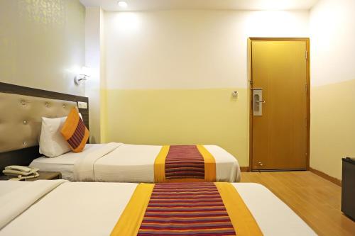 a hotel room with two beds and a door at Hotel Aeroporto in New Delhi