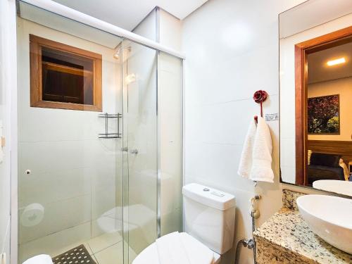 a bathroom with a shower and a toilet and a sink at Solar da Encosta 305 - Espaço e conforto no Centro in Gramado