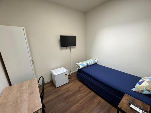 a bedroom with a bed and a tv on the wall at Backpackers Central Hamilton in Hamilton