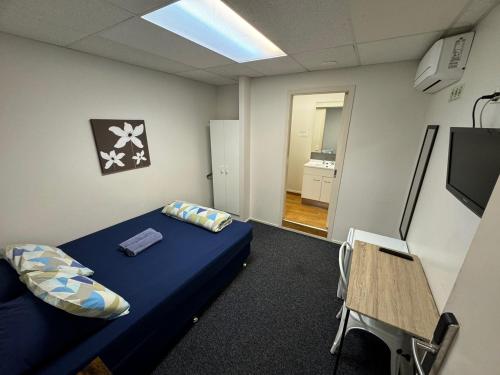 a room with a bed and a table and a tv at Backpackers Central Hamilton in Hamilton