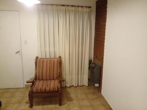 a living room with a chair and a curtain at Orly Apart in Comodoro Rivadavia