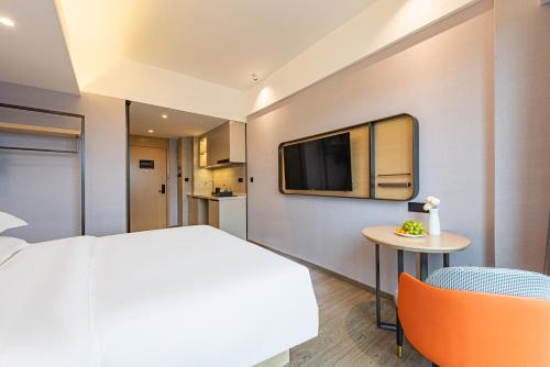 a hotel room with a bed and a tv at Poltton International Apartment - Guangzhou Knowledge City Wangcun Subway Station in Jiufo