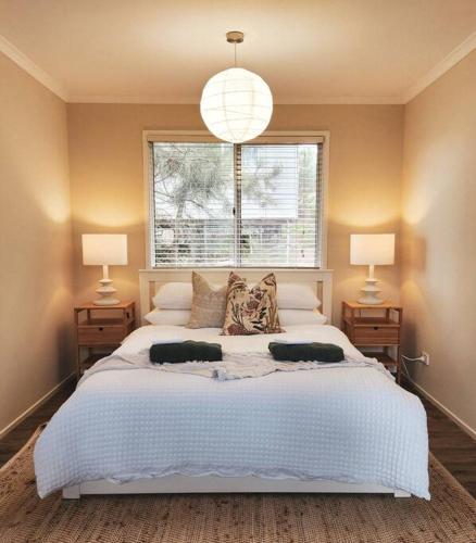 a bedroom with a large white bed with two lamps at Banksia Retreat, A couple's sanctuary on Aldinga Beach in Aldinga Beach