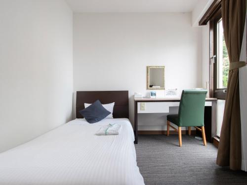 a bedroom with a bed and a desk and a chair at Tabist Sasebo Palace Hotel in Sasebo