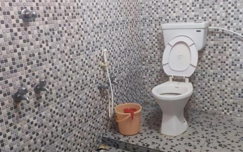 a bathroom with a toilet and a trash can at Panchak Homestay by StayApart in Mādāri Hāt
