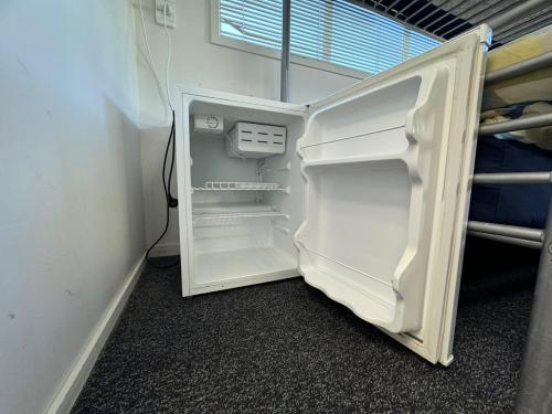 an empty refrigerator with its door open in a room at Backpackers Central Hamilton in Hamilton