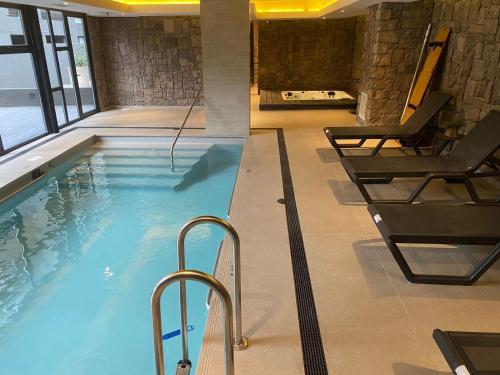a swimming pool with two chairs in a building at Maravilloso Depto nuevo 2D 2B centro frente al lago con piscina techada temperada y jacuzzi in Puerto Varas