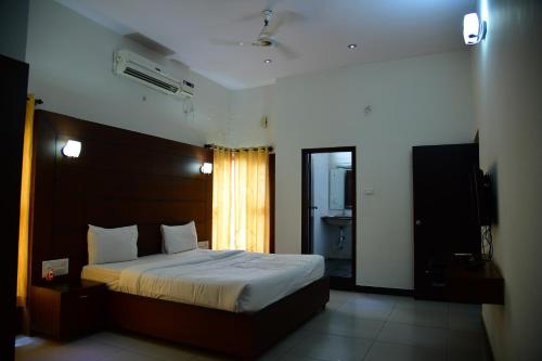 a bedroom with a large bed and a bathroom at Nijaguna Resorts in Chāmrājnagar