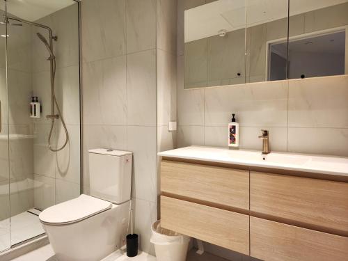 a bathroom with a toilet and a sink and a shower at U Suites on Oriental Parade in Wellington