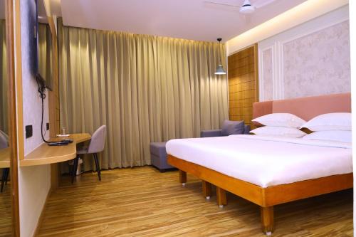 a hotel room with a bed and a desk at Hotel Surguru in Puducherry