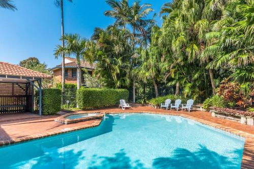 a swimming pool in a yard with palm trees at Calinda Sol 10 in Byron Bay