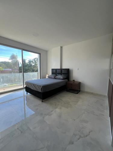 ein Schlafzimmer mit einem Bett und einem großen Fenster in der Unterkunft Estudio moderno con ubicacion estrella! in Vila El Carmen