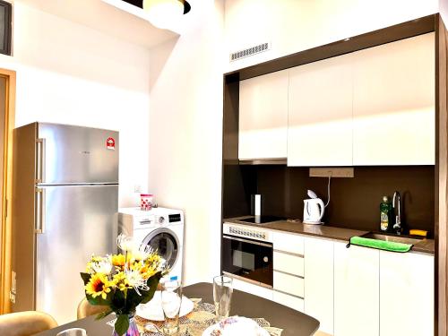 a kitchen with white cabinets and a table with flowers at The Luxe Colony KLCC By AZHA in Kuala Lumpur