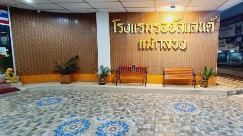 a restaurant with two benches and a sign on the wall at Royal Land Mae Klong Hotel in Samut Songkhram