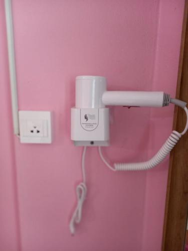 a pink wall with a phone plugged into a socket at Royal Land Mae Klong Hotel in Samut Songkhram