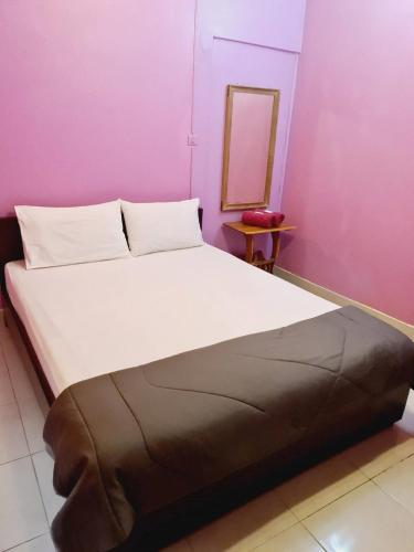 a large bed in a room with a pink wall at Royal Land Mae Klong Hotel in Samut Songkhram