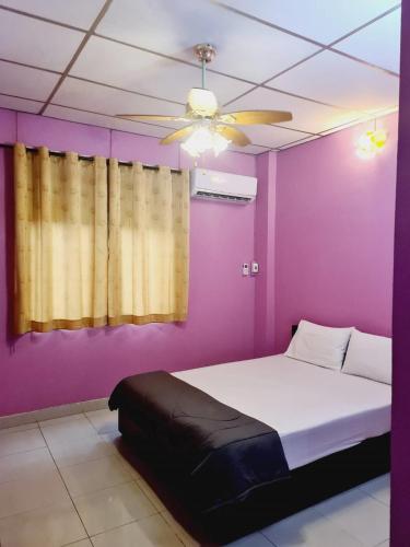 a purple bedroom with a bed and a ceiling fan at Royal Land Mae Klong Hotel in Samut Songkhram