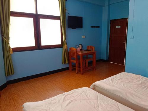 a room with two beds and a table with a chair at Royal Land Mae Klong Hotel in Samut Songkhram