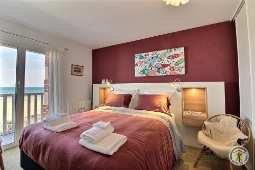 Un dormitorio con una cama grande con una pared roja. en L'emeraude, en Plérin