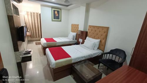a hotel room with two beds and a chair at Hotel Ranjeet Akola in Akola