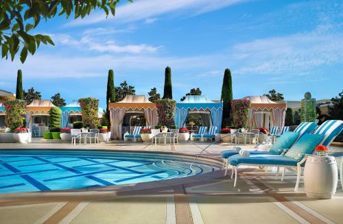 une piscine avec des chaises et des tables bleues et un bâtiment dans l'établissement Wynn Las Vegas, à Las Vegas