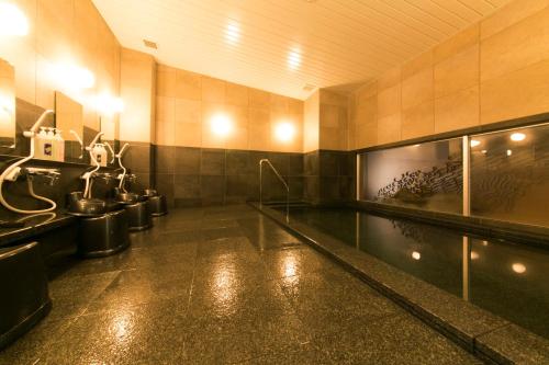 baño grande con piscina y aseos en AB Hotel Ichinomiya en Ichinomiya