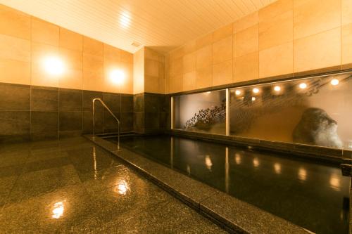 a swimming pool in a building with a painting of a dinosaur at AB Hotel Ichinomiya in Ichinomiya