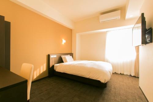a hotel room with a bed and a window at AB Hotel Ichinomiya in Ichinomiya