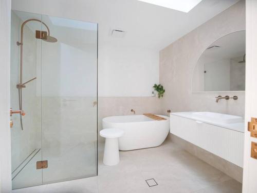 a bathroom with a shower and a tub and a sink at Luxury Home in the Vale in Berkeley Vale